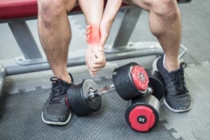 Mann som viser tegn til smerte i håndleddet etter styrketrening på gym