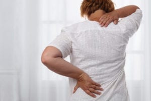 Kvinne som viser tegn til smerte i nakke og rygg